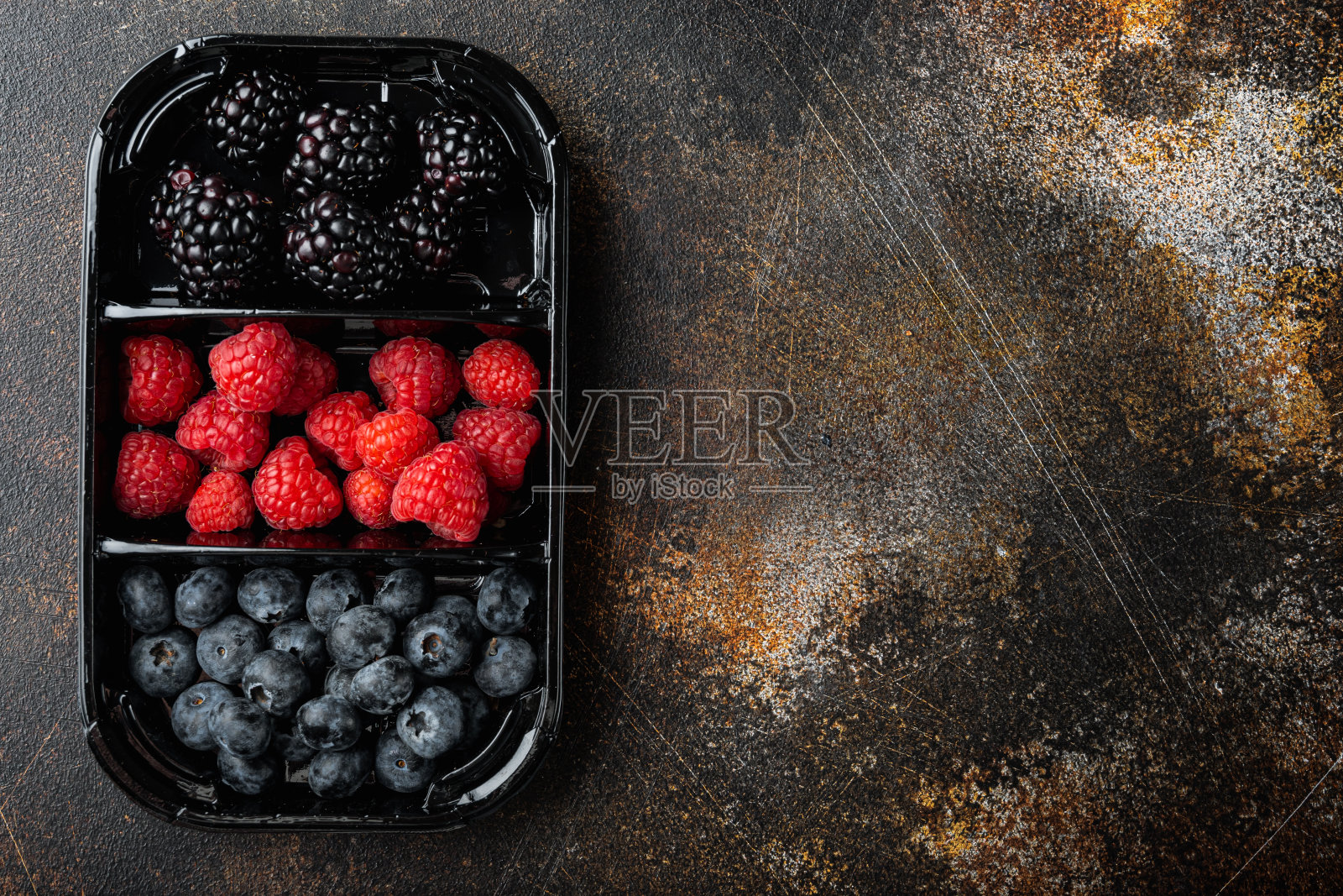 成熟的浆果托盘从市场，蓝莓，覆盆子和黑莓，俯视图与复印空间，在旧的深色桌子上照片摄影图片