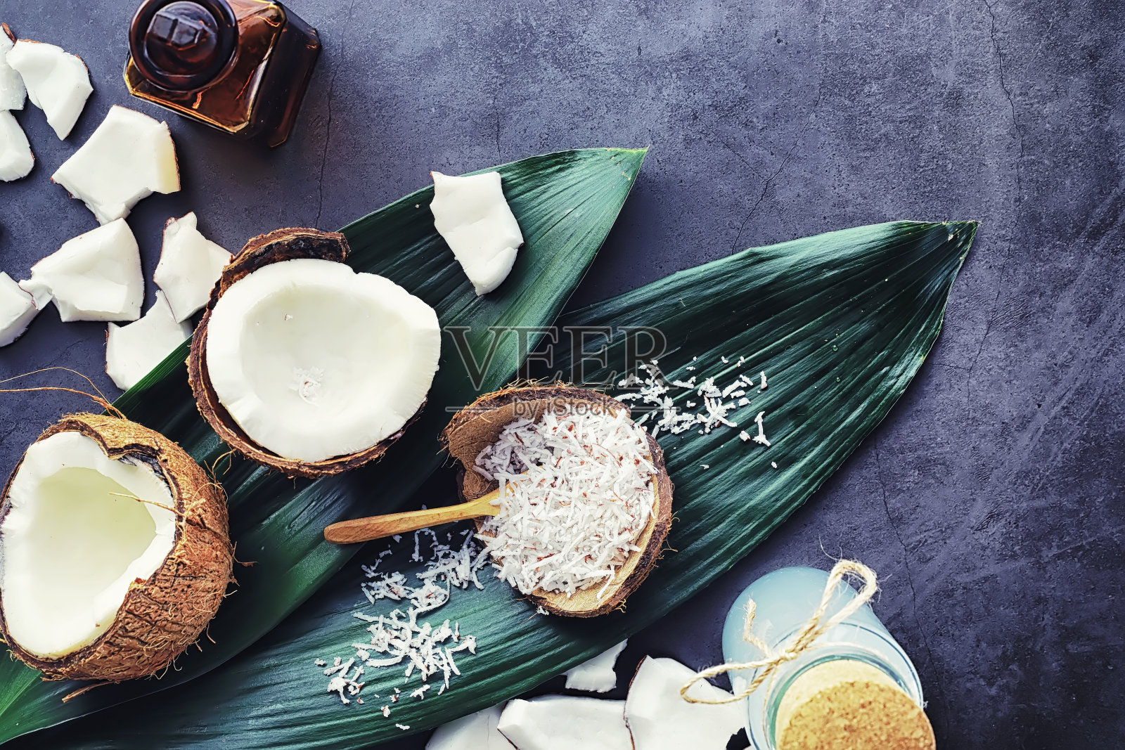 深色的石头桌上放着椰子。椰子油。照片摄影图片