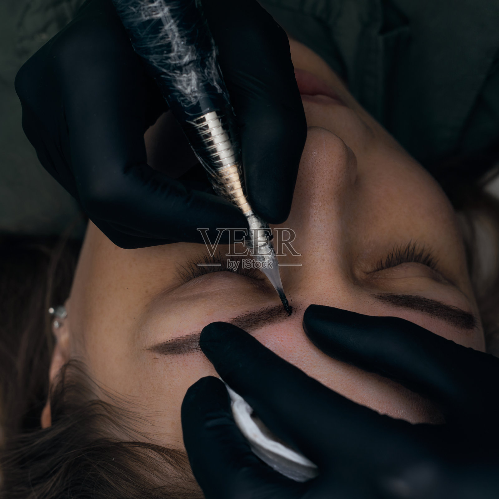 永久眉妆程序。眉纹身的过程。使用工具的大师为永久眉妆。照片摄影图片