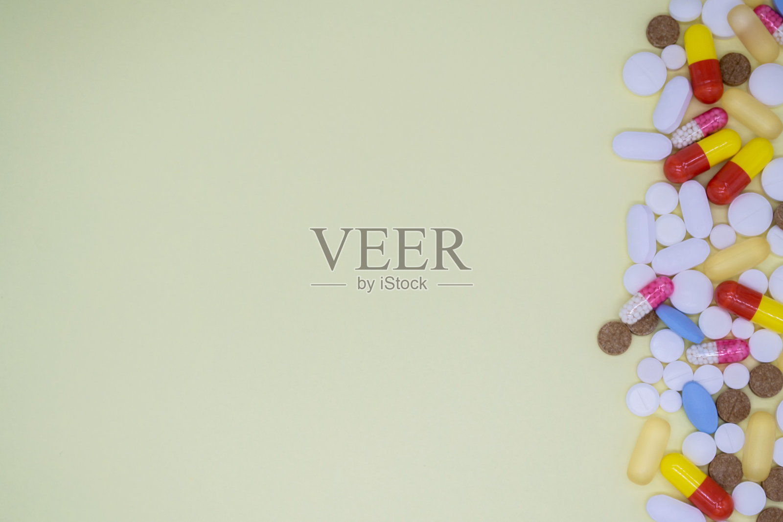 右边是很多五颜六色的药片和药片。黄色背景，拷贝空间照片摄影图片