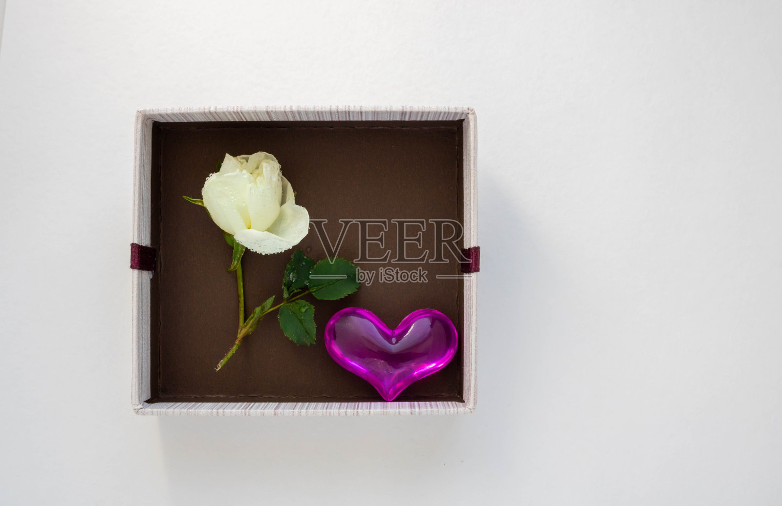 礼物棕色盒子，一个心和白玫瑰在白色的背景。情人节、周年纪念、母亲节、3月8日和生日问候的概念。文本空间照片摄影图片