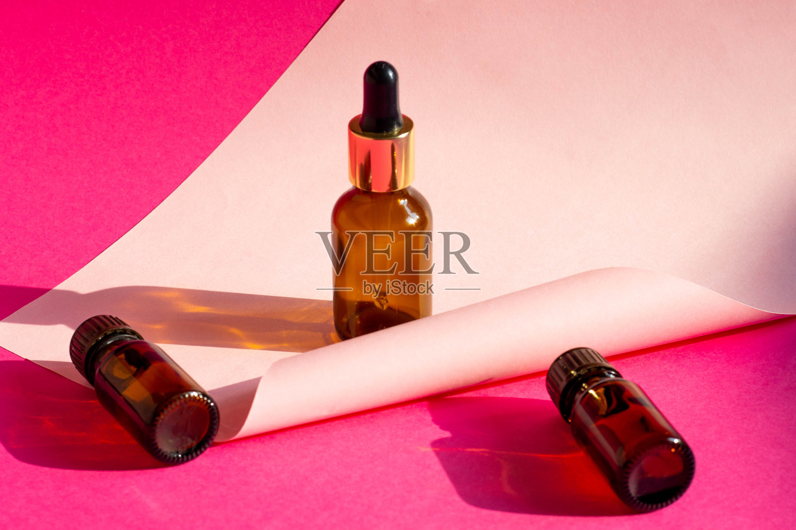 玻璃化妆品瓶在明亮的粉红色背景与硬阴影。美容博客，程序沙龙概念。极简主义。粉色背景上的化妆品滴管。照片摄影图片