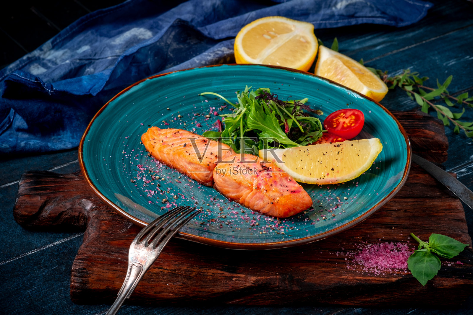 烤鲑鱼排配绿色沙拉和西红柿在深色木制背景上。含有欧米加3的健康饮食照片摄影图片