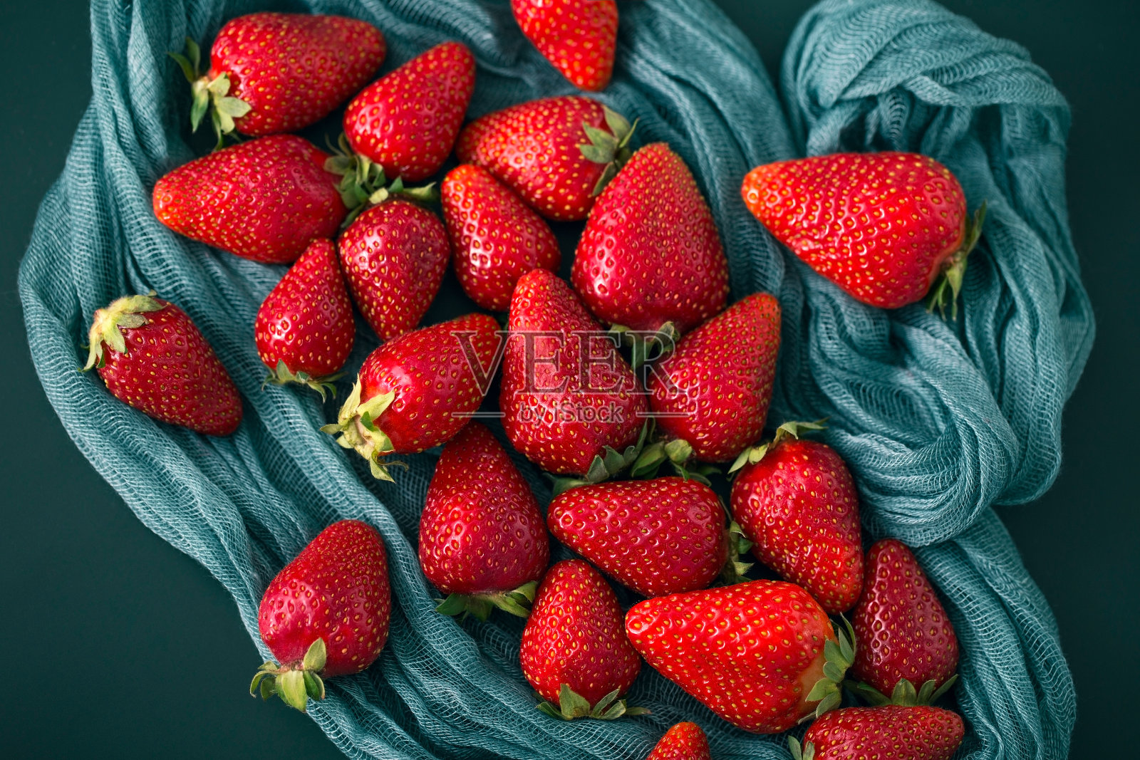 纱布上的红草莓。新鲜成熟的浆果在深绿色的织物背景照片摄影图片