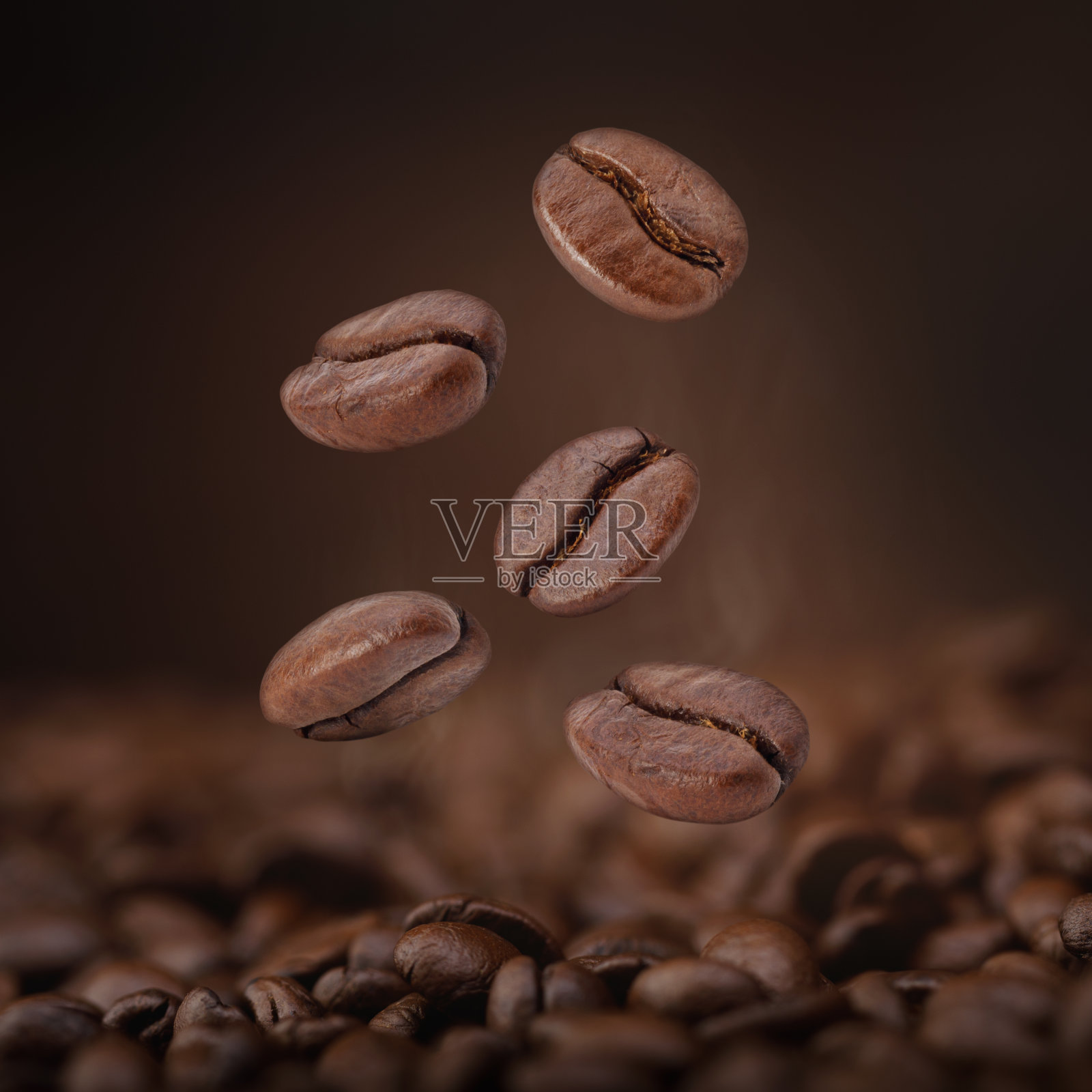 热的棕色烘培咖啡豆从空气中掉落在棕色的背景下，由有机天然成分概念的健康产品照片摄影图片