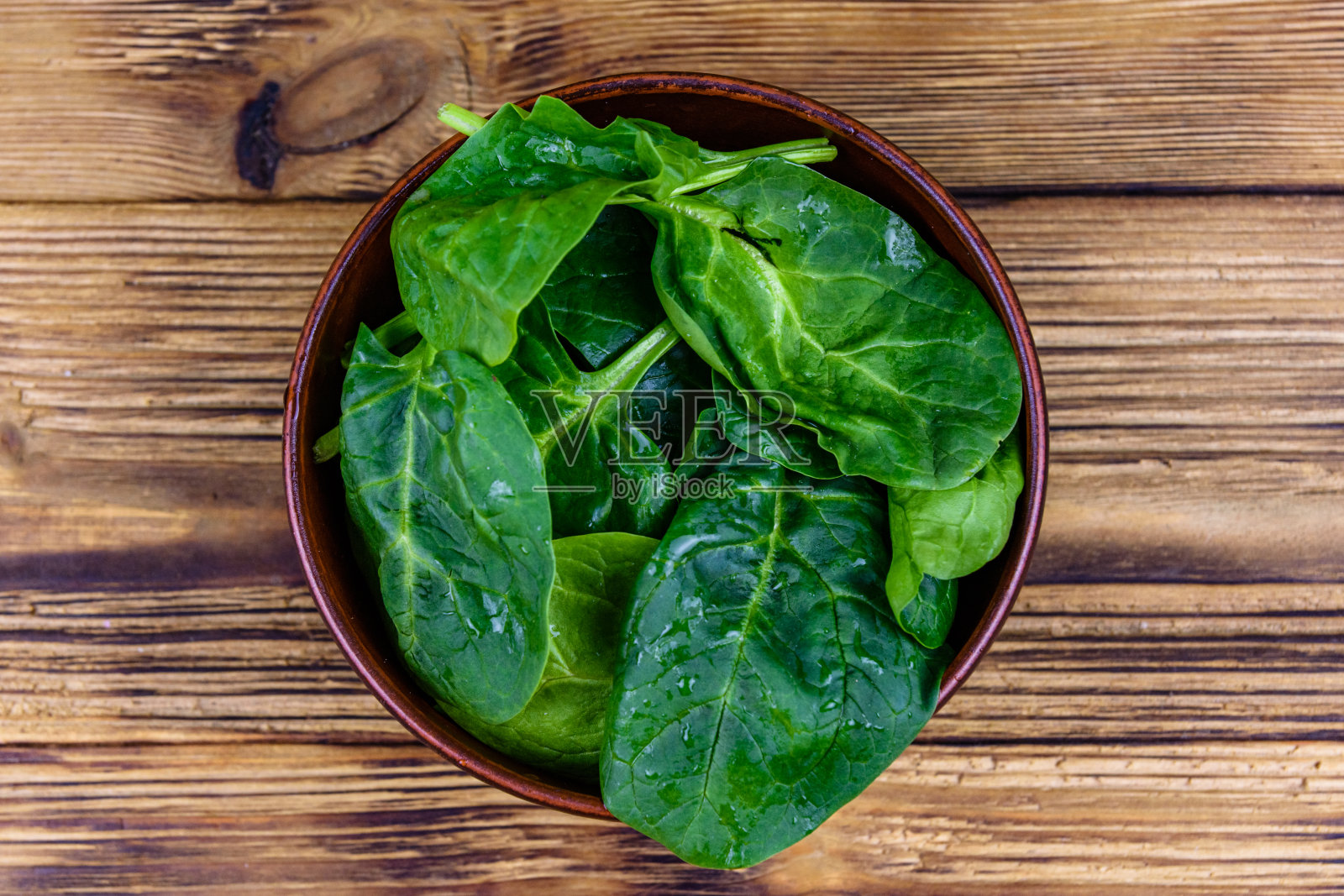 陶瓷碗，菠菜叶，质朴的木桌。俯视图照片摄影图片