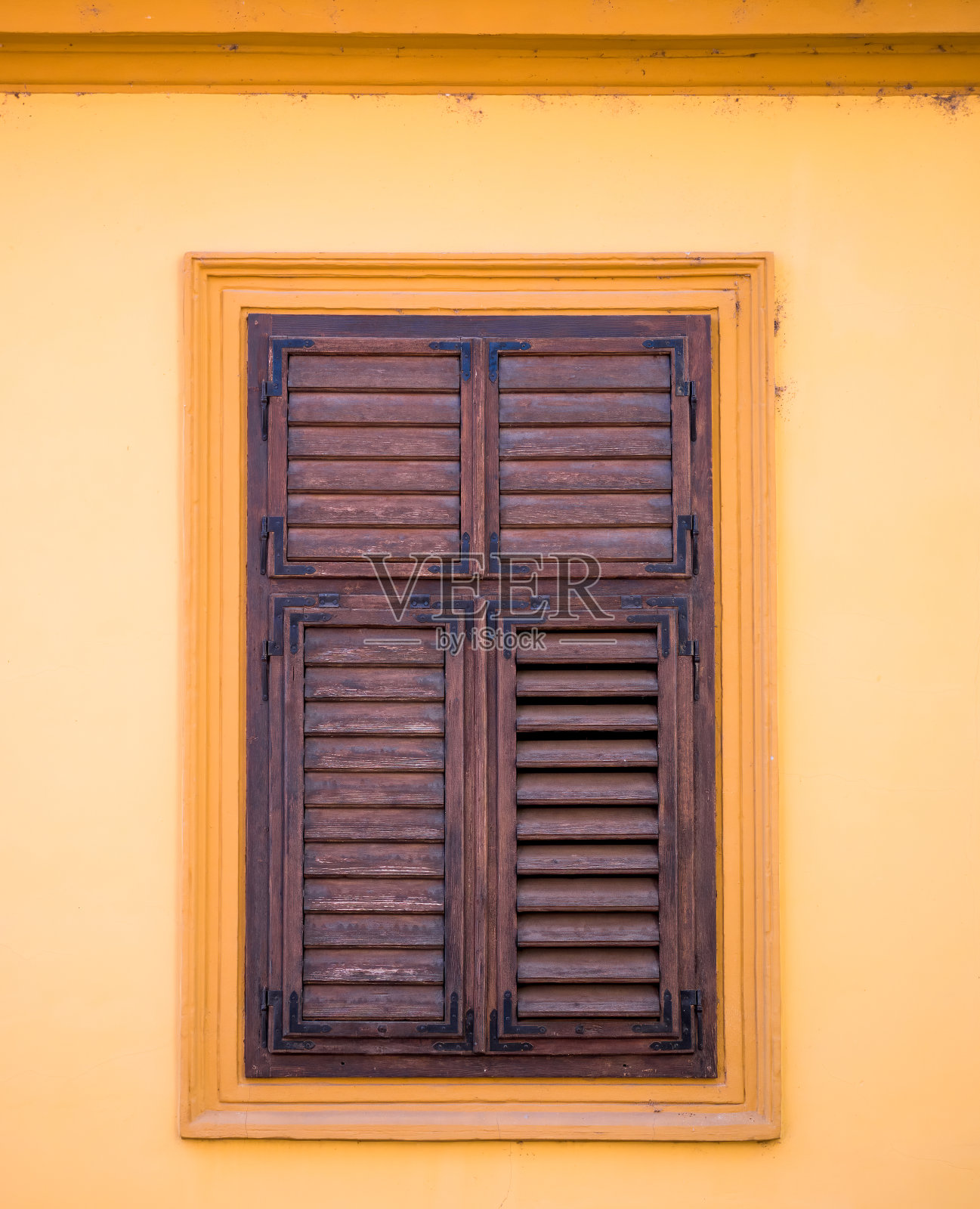 罗马尼亚希基索瓦拉中世纪小镇的橙色墙壁上，一扇带有旧木百叶窗的窗户。照片摄影图片