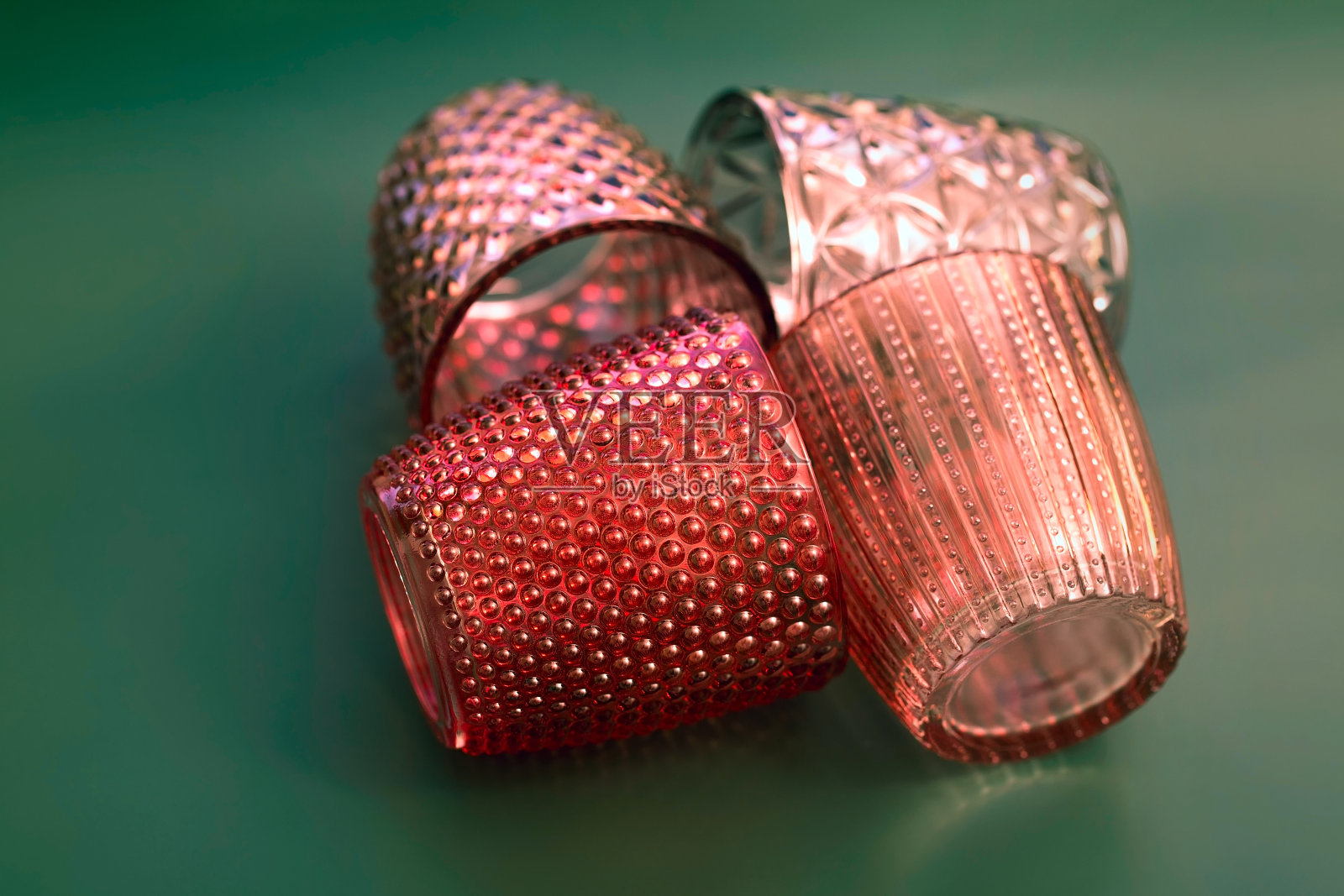 有图案的彩色玻璃，红色的蜡烛杯叠在绿色的背景上照片摄影图片