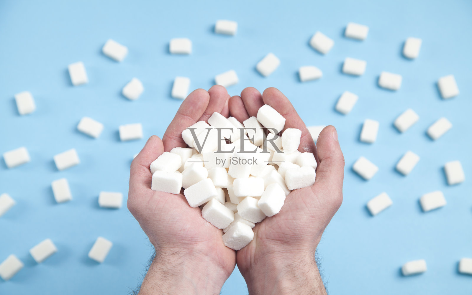 蓝色背景上的男性手拿着方糖。照片摄影图片
