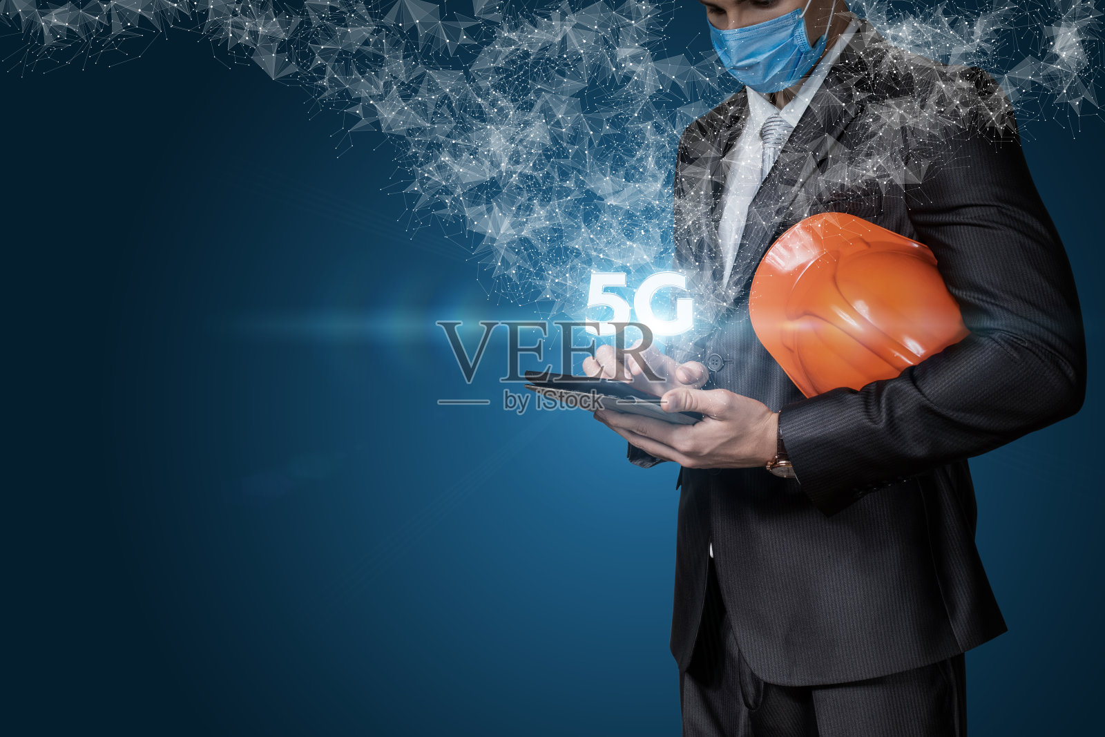 一名手持防护头盔的商人在看5G标志的平板电脑。照片摄影图片