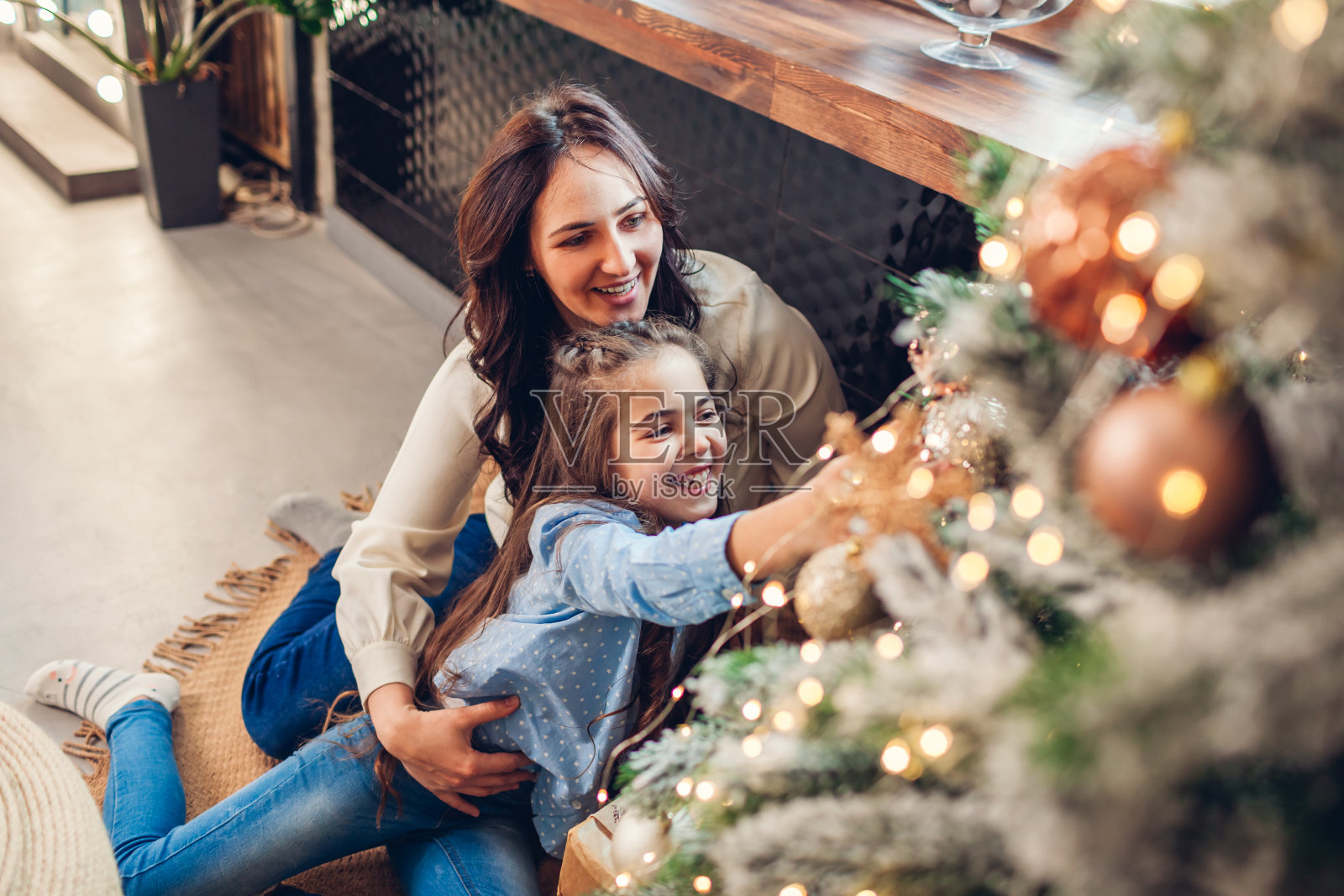 母亲和女儿在家欣赏圣诞树。圣诞快乐，恭贺新禧。家庭的乐趣照片摄影图片