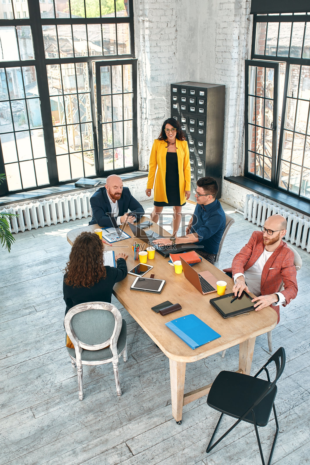 在办公室开会时，漂亮的商务人士正在使用电子设备，谈笑风生。有选择性的重点照片摄影图片