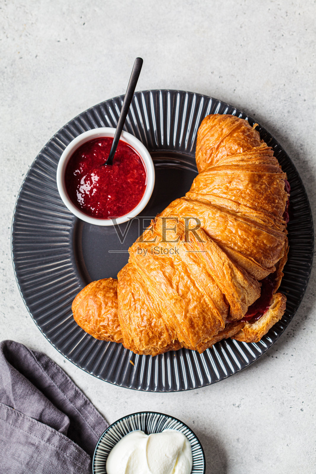 灰色盘子上的新鲜牛角面包配奶油和浆果酱，俯视图。美味的早餐概念。照片摄影图片