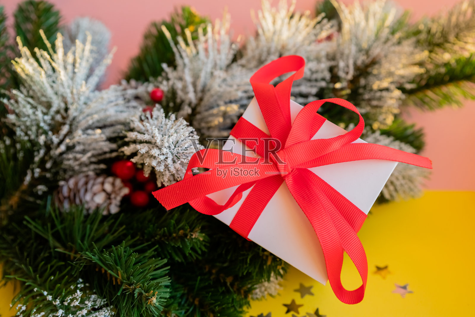 圣诞节。圣诞和新年礼盒和装饰孤立在黄色背景。节日设计组成。礼盒上装饰着红丝带蝴蝶结，松树树枝。照片摄影图片