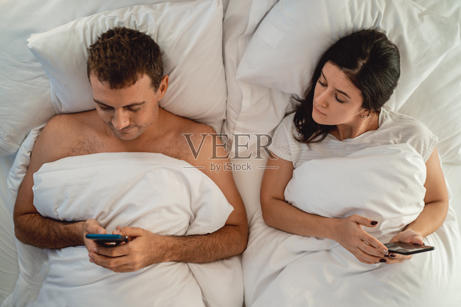 夫妻俩躺在床上玩智能手机照片摄影图片