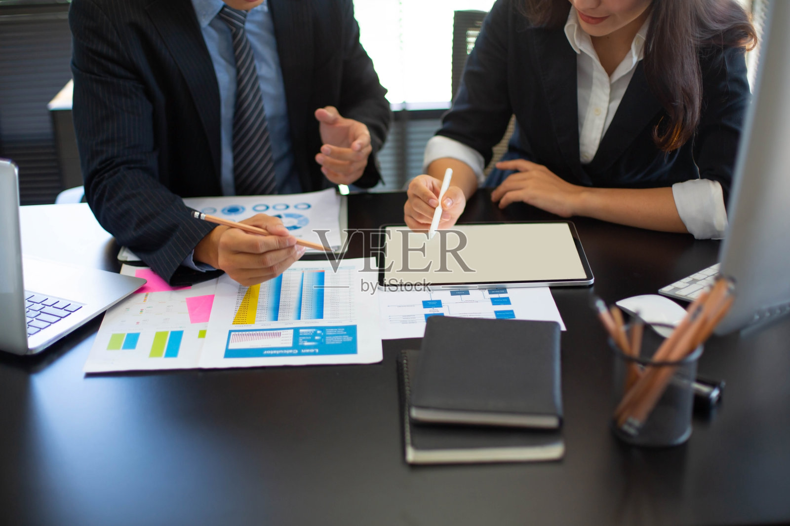 两个商人或雇员使用个人电脑和营销图表一起分析一起经营企业的收入、费用和利润。照片摄影图片