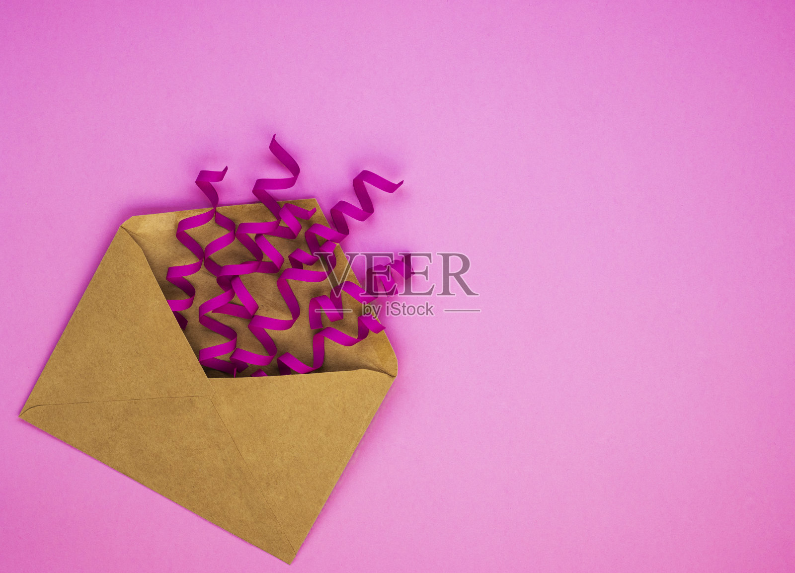 美丽的工艺信封与紫色的五彩纸屑在粉红色的背景照片摄影图片