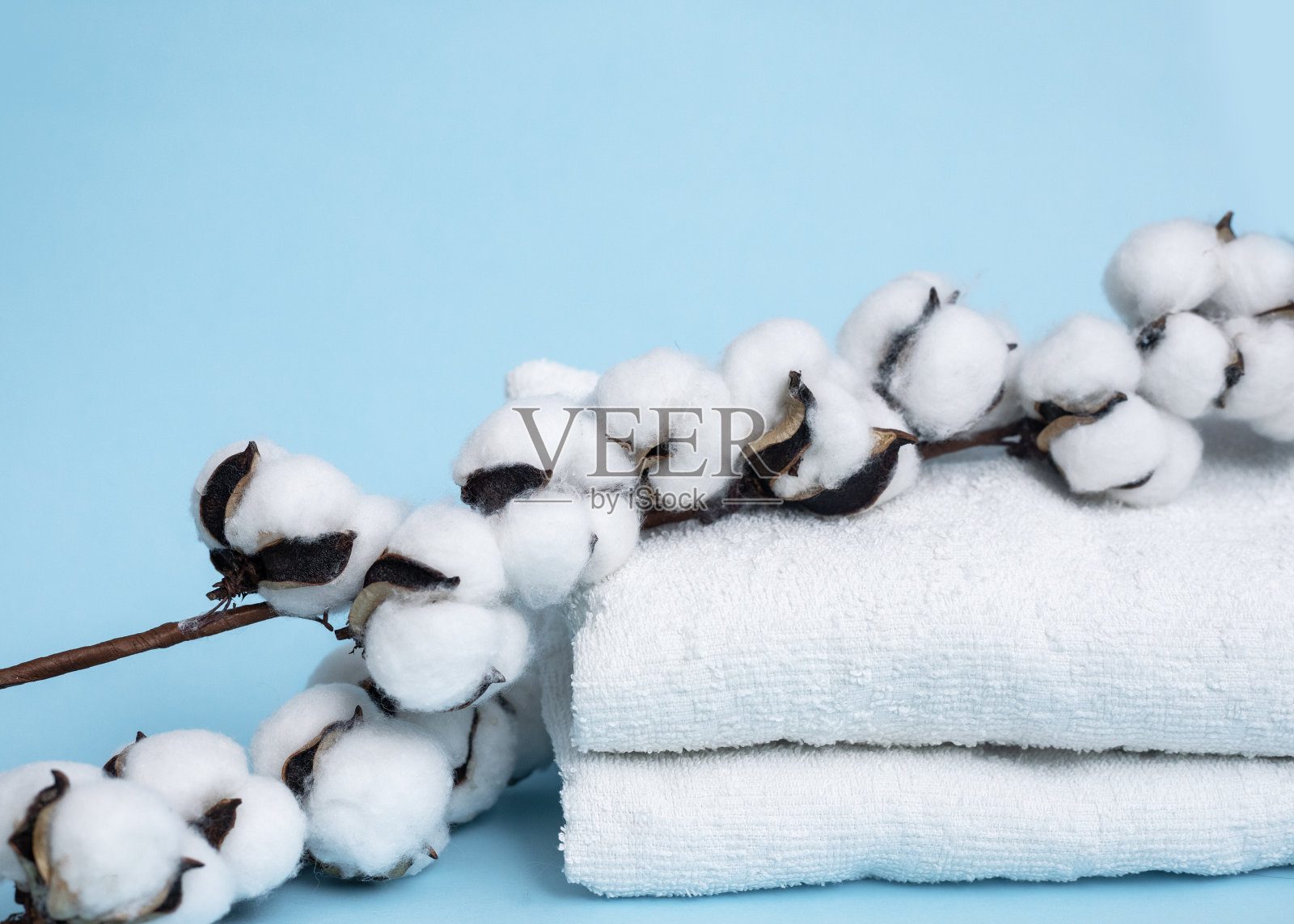 蓝色背景上的一束棉布和一叠白色毛巾。前视图。自然纤维的概念。本空间照片摄影图片