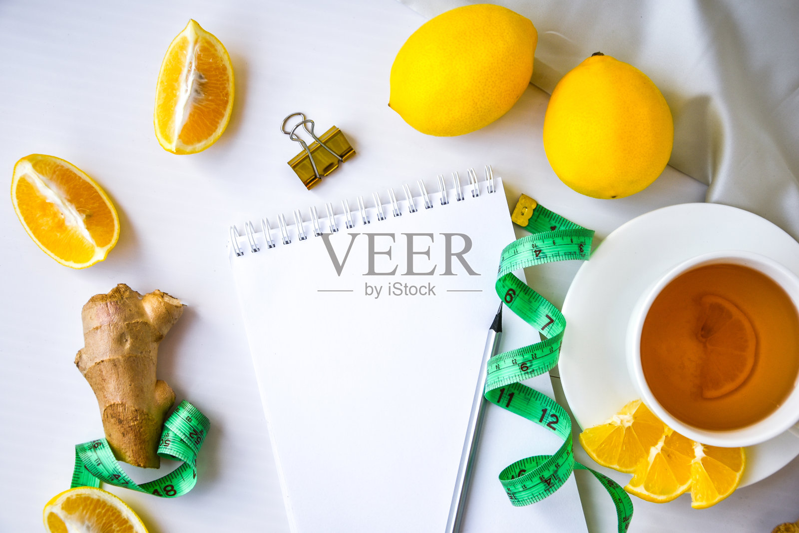 健康概念柠檬，姜，甘菊茶，测量卷尺在白色的背景。用铅笔和空白的空间清空笔记本照片摄影图片