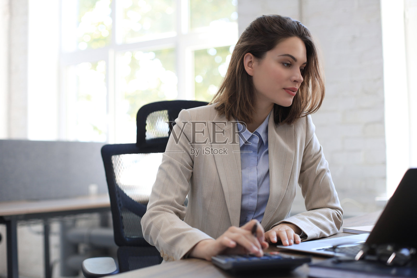 漂亮开朗的商务女性在现代办公室用笔记本电脑工作。照片摄影图片