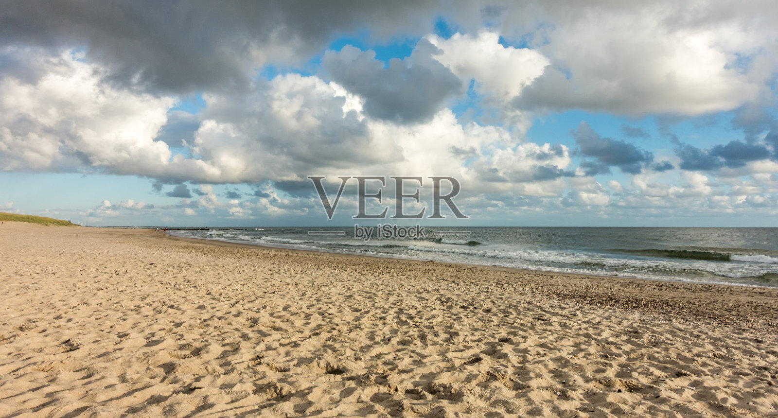 海滩沙子与蓝天和戏剧性的云在海岸线滨水在柔和的黄昏日落光。Hvidbjerg Strand，布拉旺，北海，丹麦。照片摄影图片