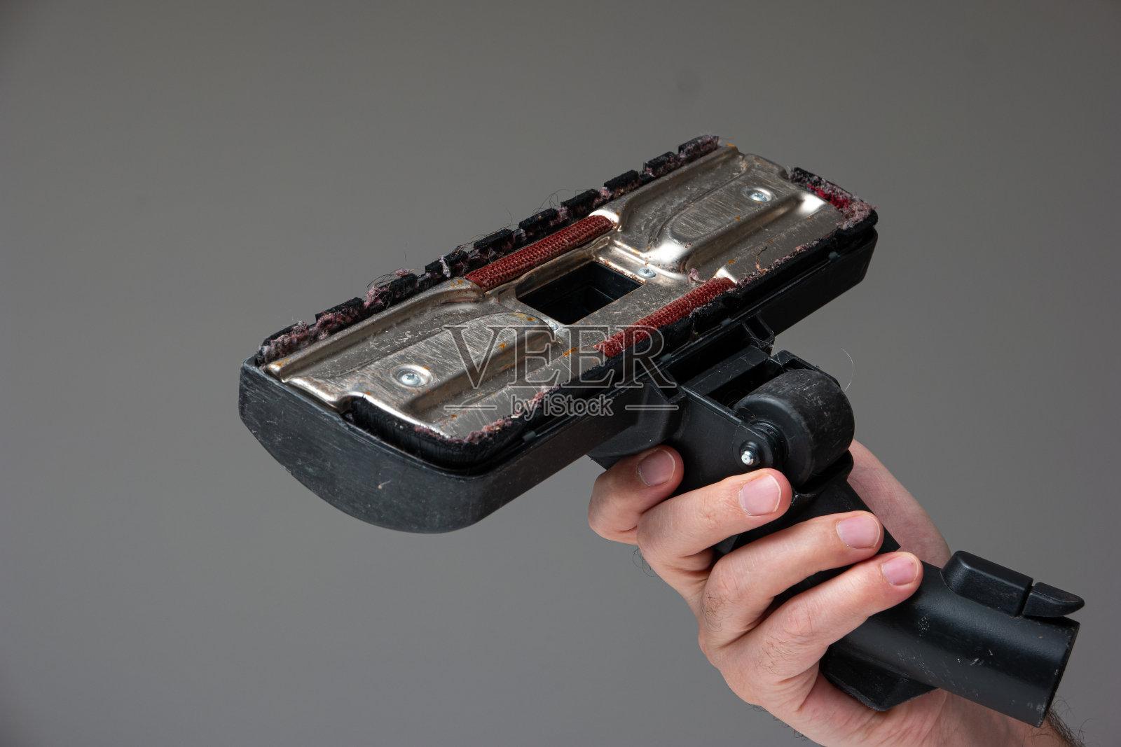 白人男性的手拿着一个旧的用肮脏的吸尘器刷附件与头发和灰尘近距离拍摄孤立的射线背景照片摄影图片