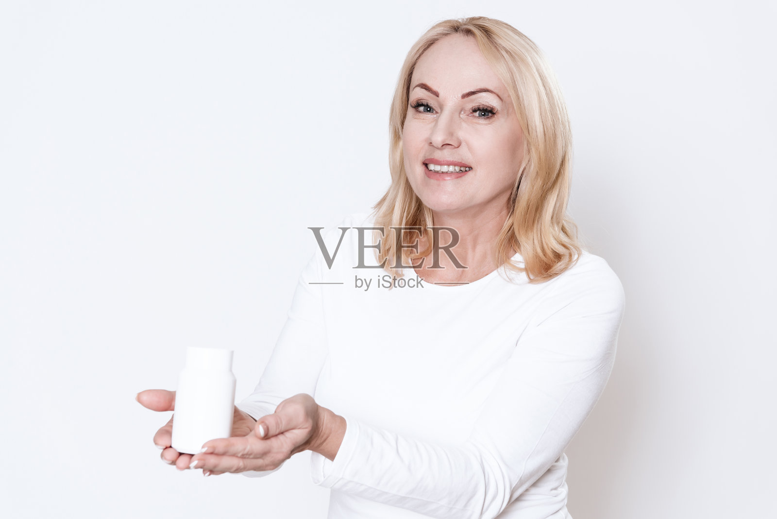 成年妇女拿着药，看着摄像机。照片摄影图片