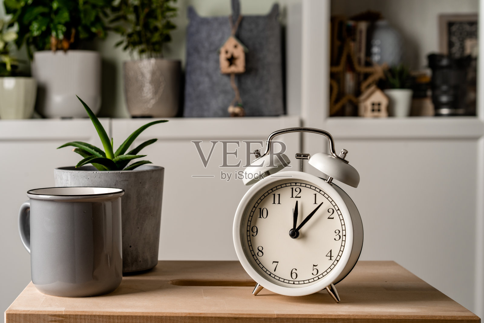 闹钟放在客厅的木桌上，室内装饰很现代，有绿色植物照片摄影图片