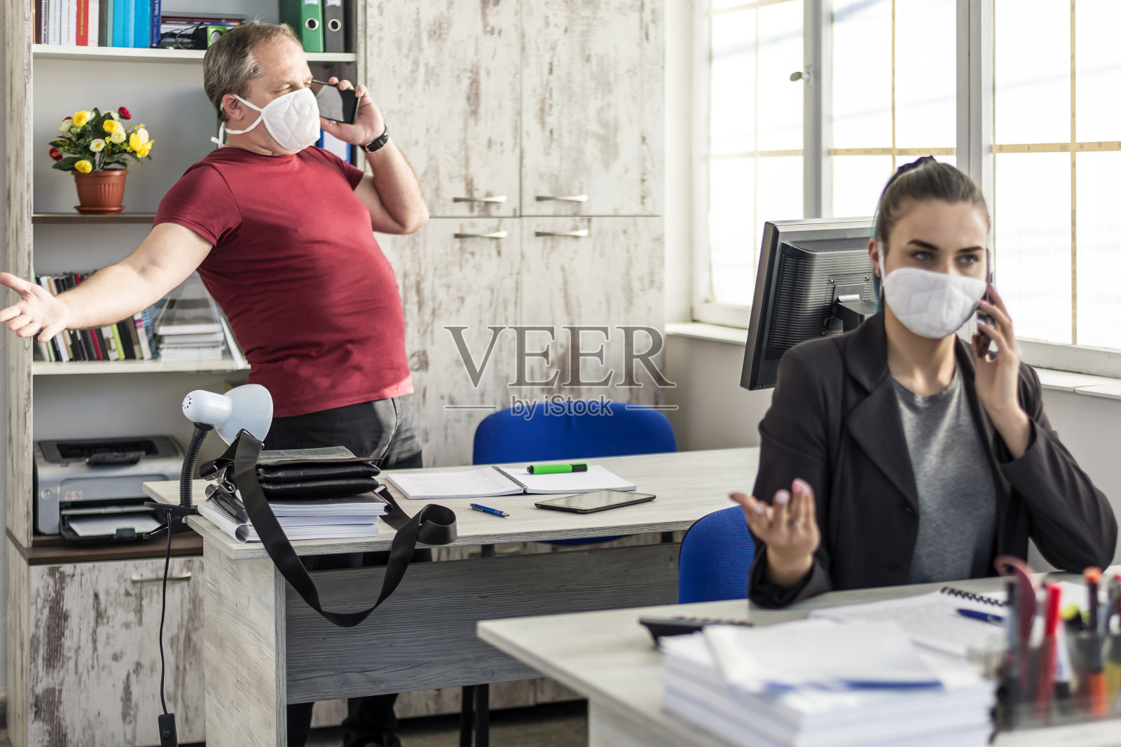 新冠肺炎疫情期间，办公室同事戴着医用口罩工作照片摄影图片