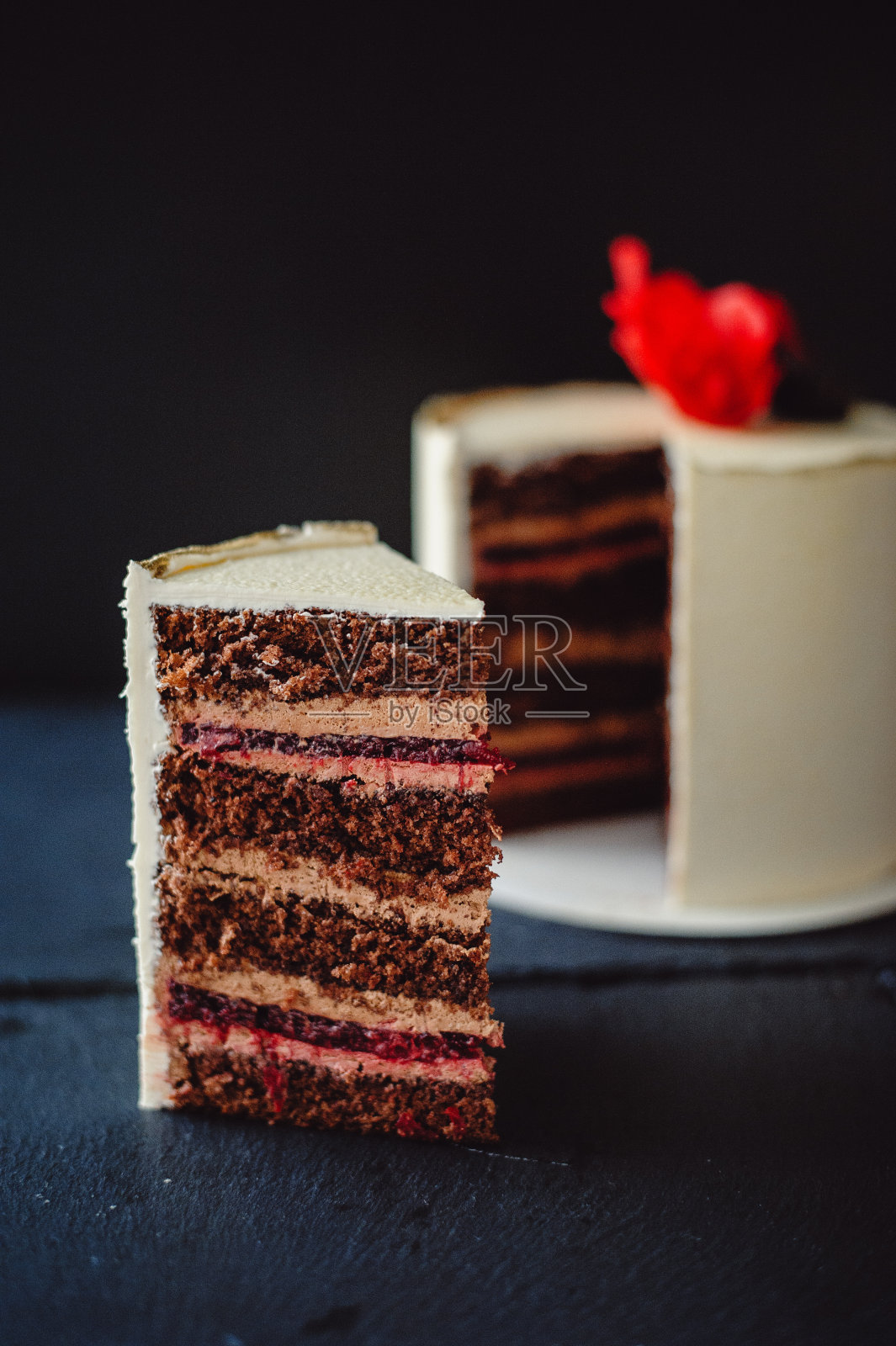 黑色背景上漂亮的巧克力蛋糕。一个美味的巧克力蛋糕和樱桃果冻。垂直的照片。照片摄影图片
