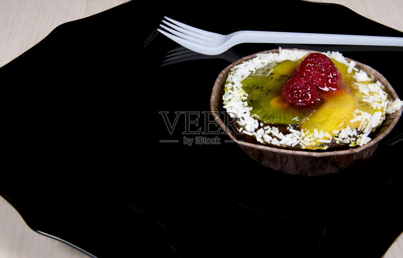 莓果馅饼或水果蛋糕和奶油果冻放在黑色的盘子里。点心甜点。副本的空间。照片摄影图片