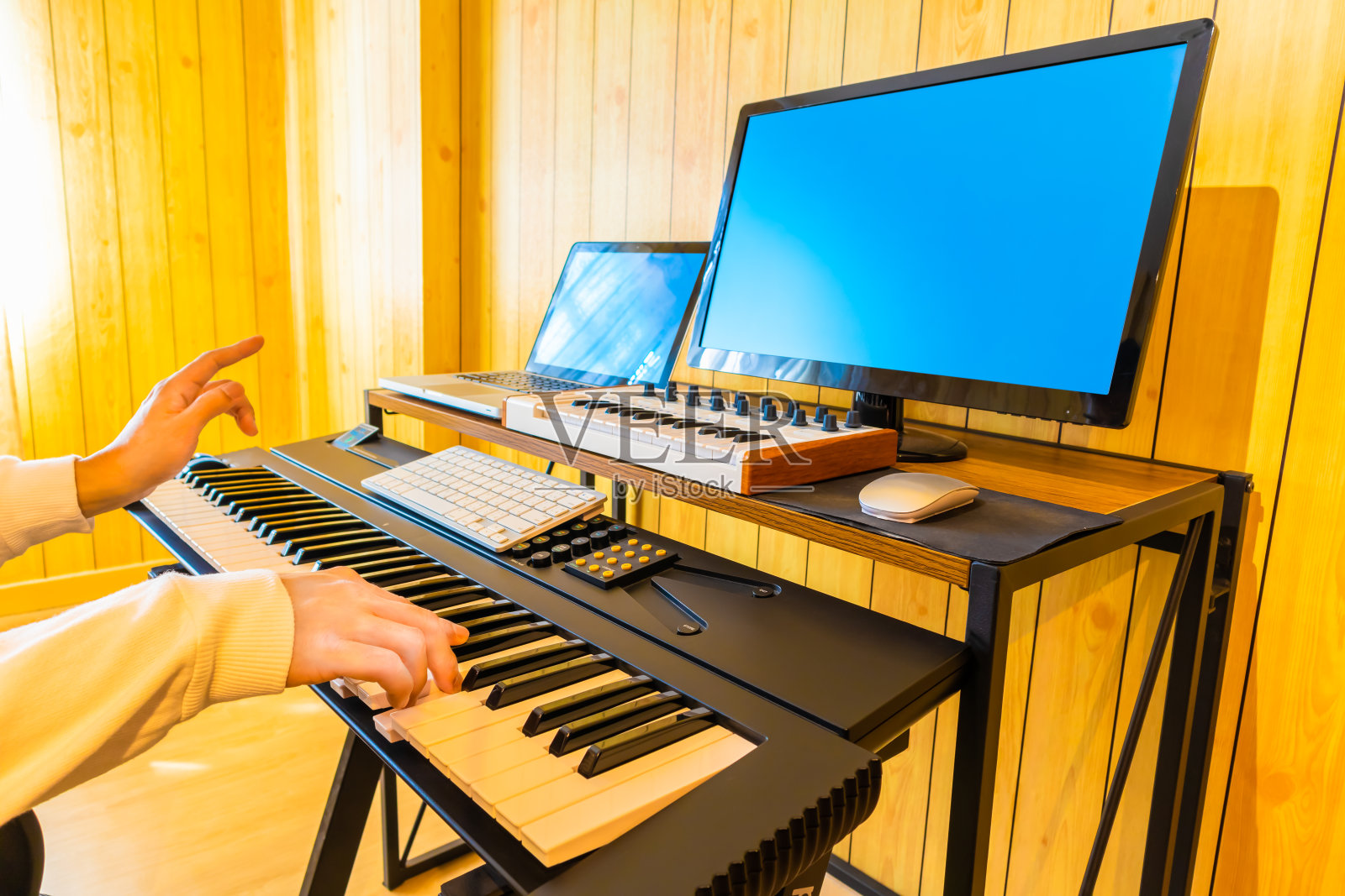 男子手弹奏数字钢琴键，同时从网上学习音乐课。音乐学习的概念照片摄影图片