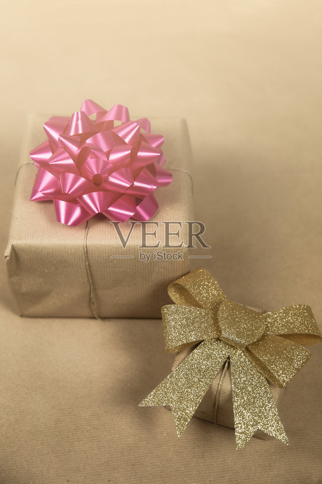 两个盒子在生态棕色普通纸与金色和粉红色包装装饰，生日礼物，情人节母亲节和其他政党的概念在棕色背景顶视图照片摄影图片