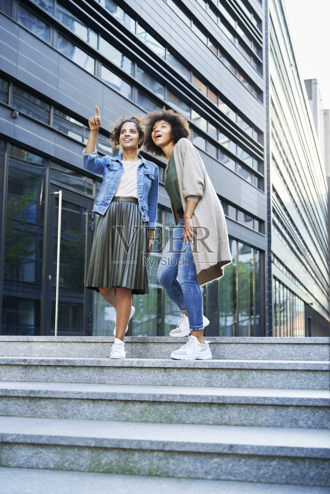 两个朋友走在城市里，指着什么东西照片摄影图片