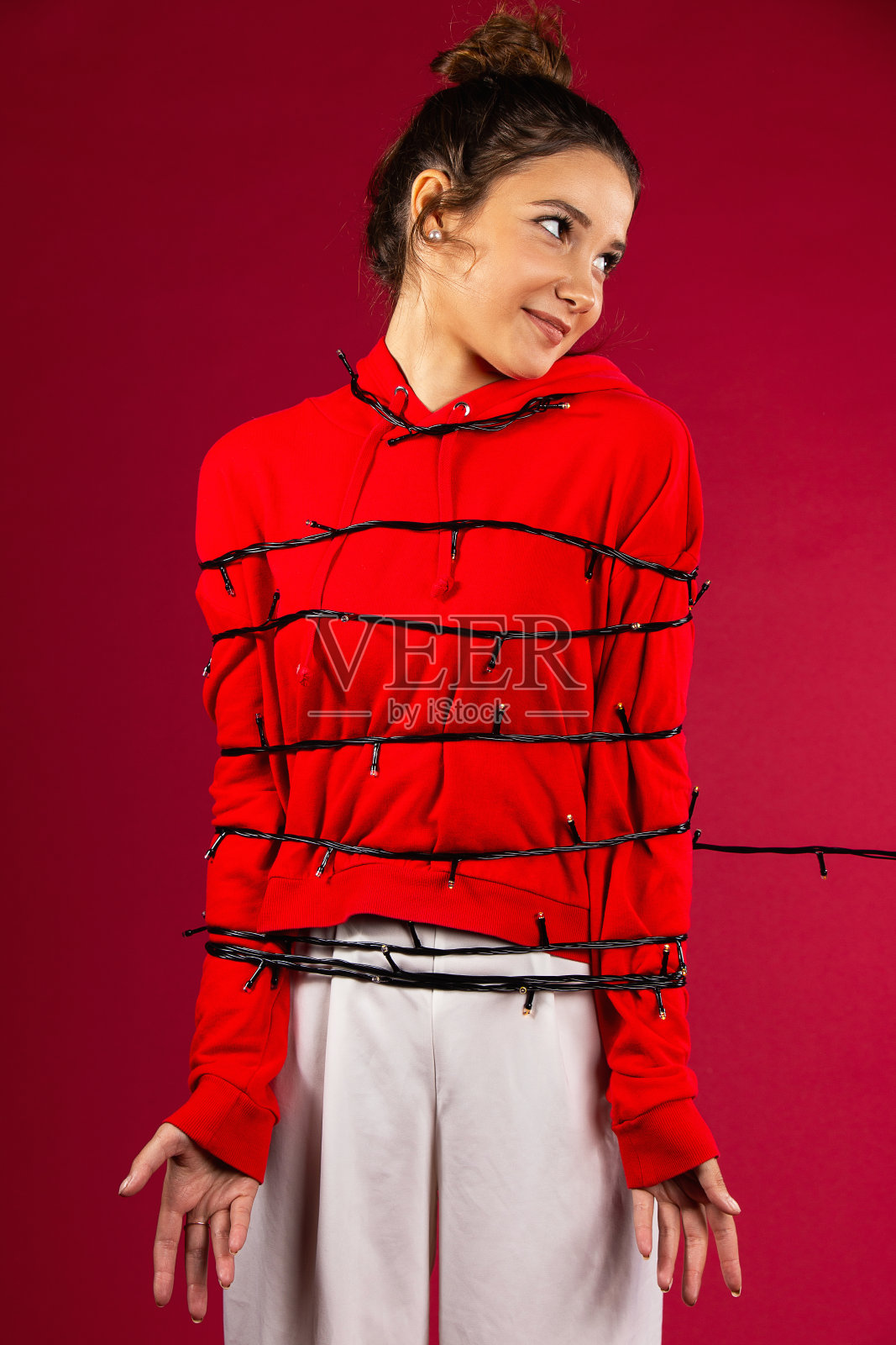 年轻美丽的白人妇女覆盖花环站在孤立的红色背景，微笑着看远照片摄影图片