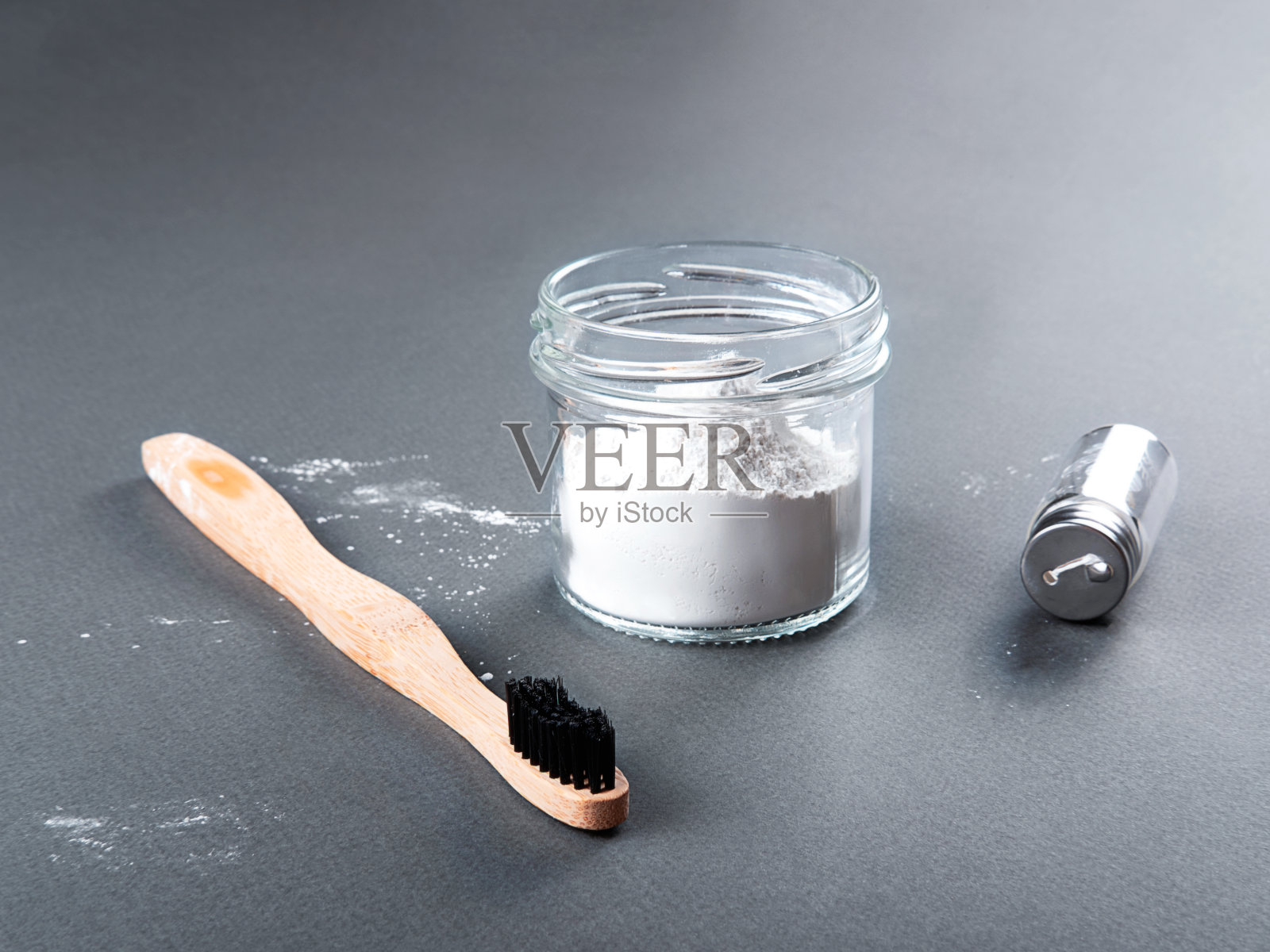 清洁牙齿零浪费理念。灰色背景的玻璃上有一把竹制牙刷，上面有牙线和牙粉。照片摄影图片