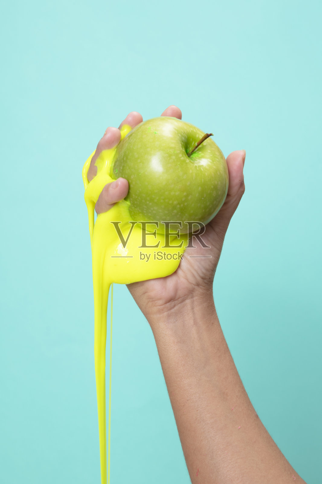 在绿纸背景上拿着绿苹果片。照片摄影图片