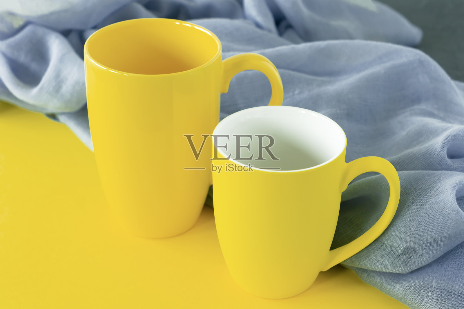 灰色和黄色背景上的两个黄色杯子。2021年的颜色照片摄影图片
