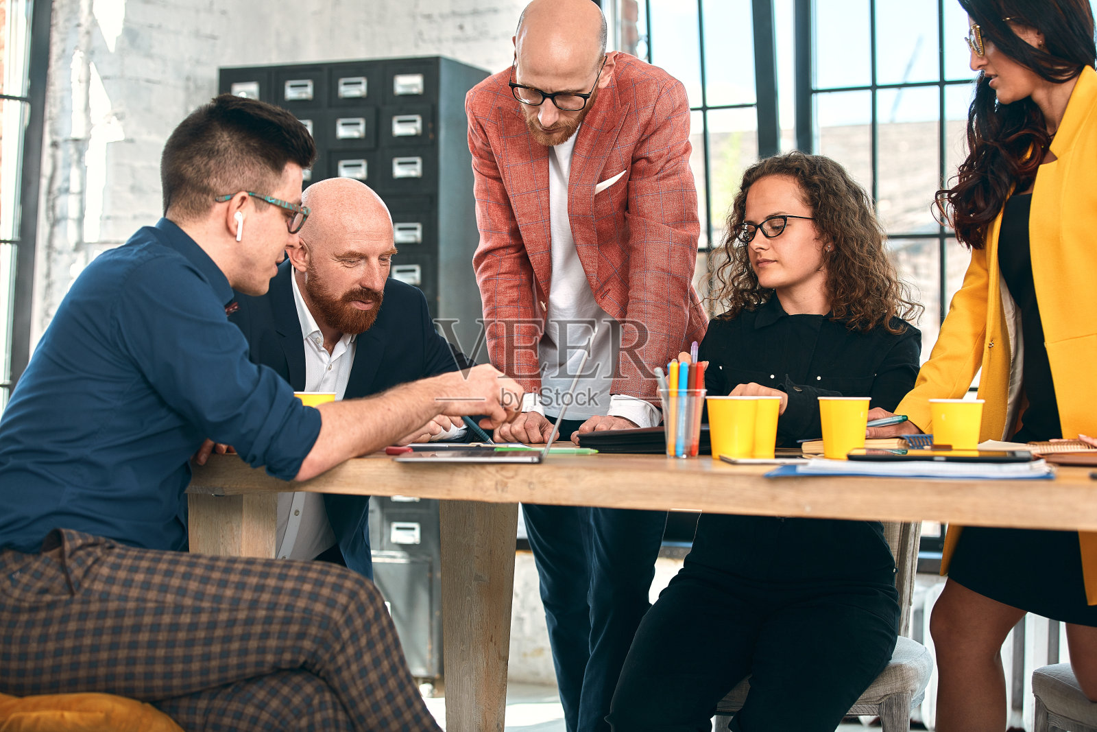 在办公室开会时，漂亮的商务人士正在使用电子设备，谈笑风生。有选择性的重点照片摄影图片