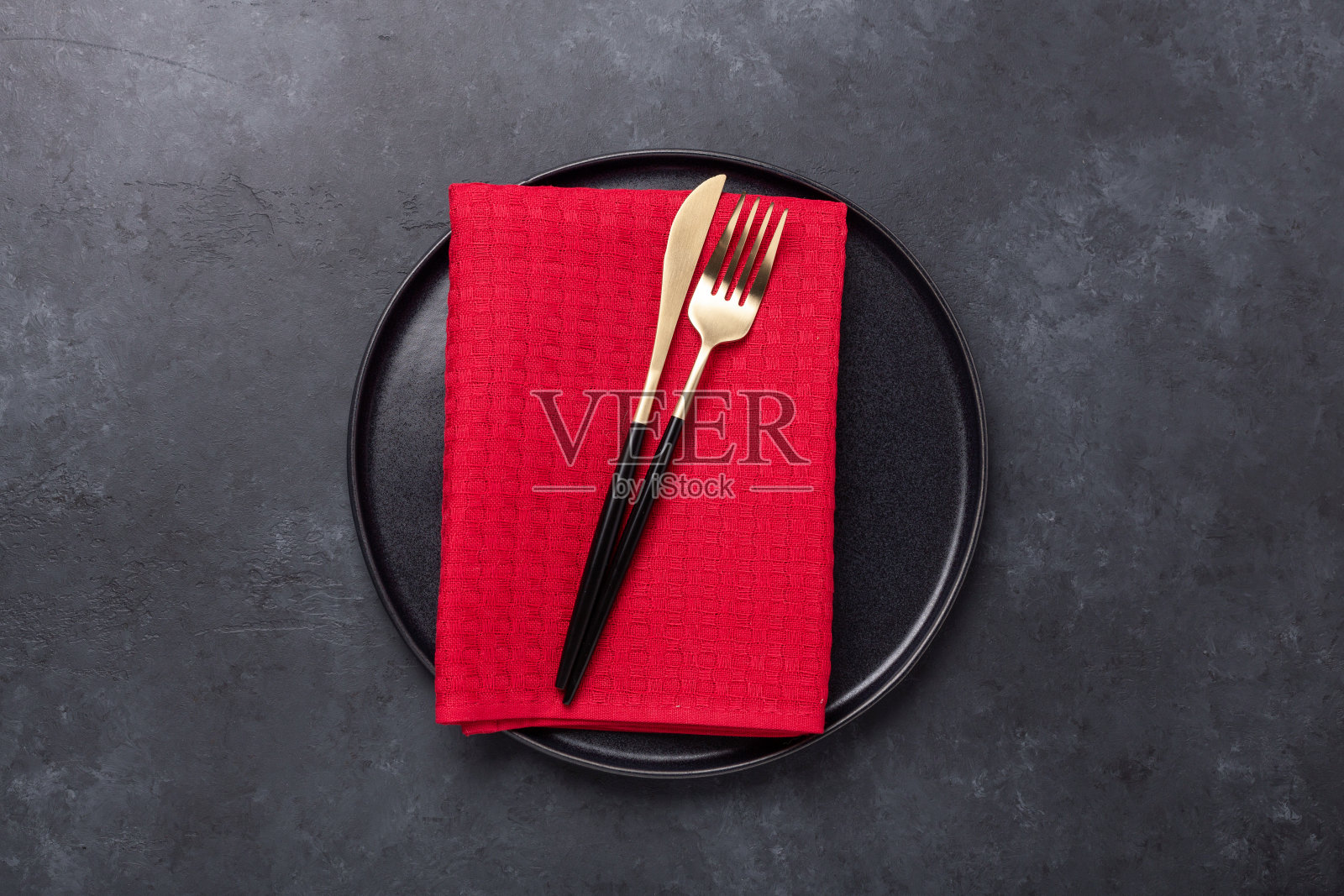 桌子设置与黑色陶瓷盘子和刀叉在黑色的石头背景。前视图。本空间照片摄影图片