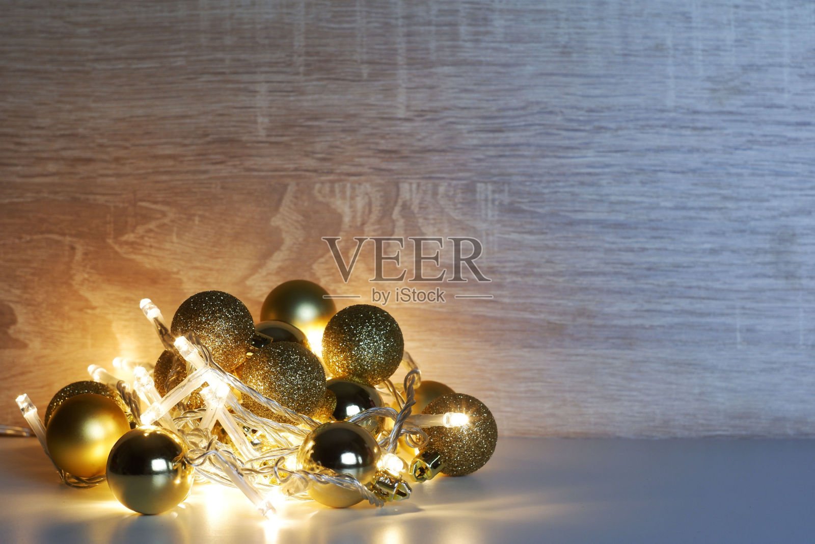 圣诞和新年模板黄金闪亮，闪闪发光，哑光圣诞球照明led花环轻橡木纹理表面与复制空间照片摄影图片