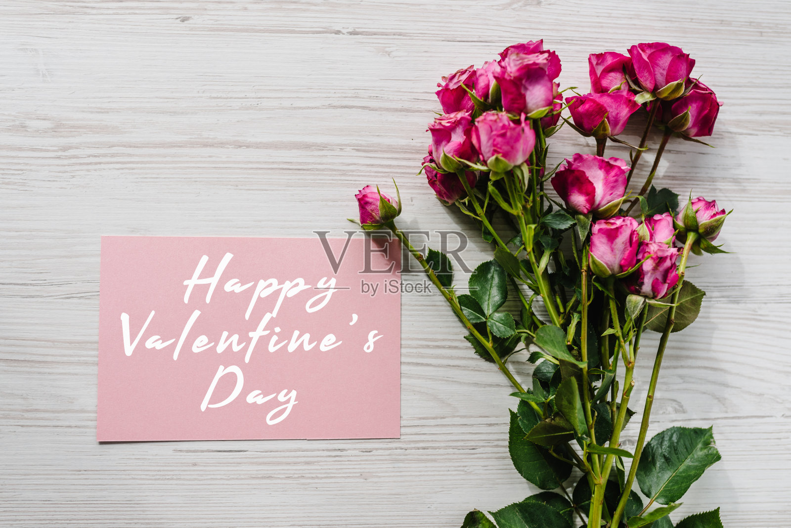 明信片上有一束小粉红玫瑰在木制背景。带文字的节日贺卡情人节快乐。俯视图，平面布局。照片摄影图片