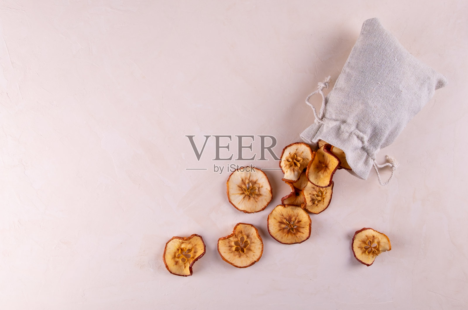 一片片的干果苹果放在一个环保袋里，放在一个轻便的表面上。照片摄影图片