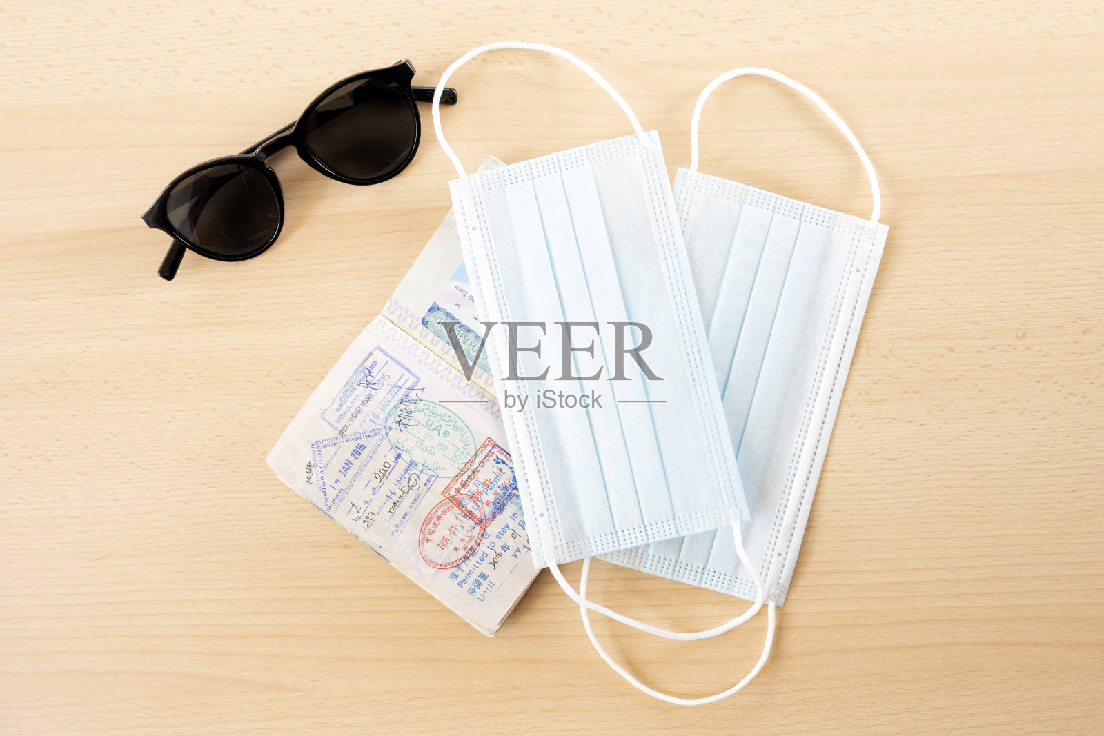 旅游概念，口罩、护照和太阳镜被安排在木桌上。照片摄影图片