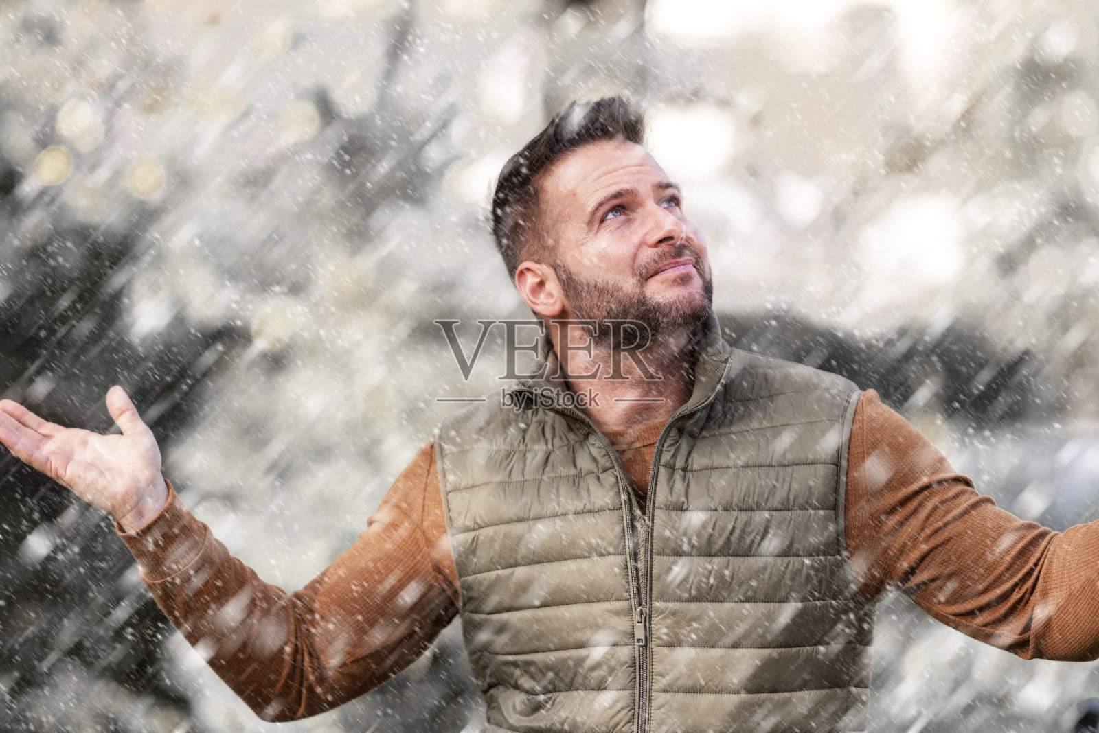 英俊微笑的男人站在外面享受雪花飘落照片摄影图片