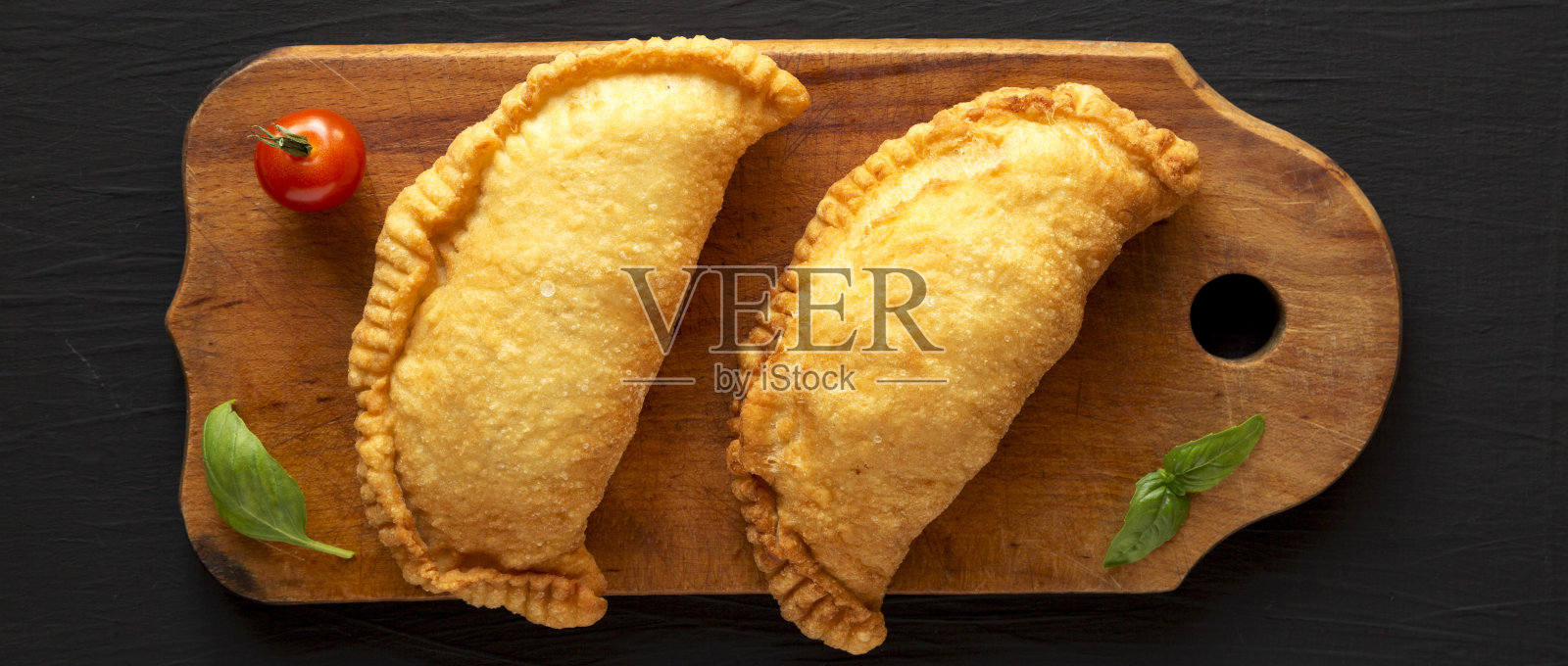 在黑色背景的乡村木板上自制的油炸意大利馅饼，俯视图。平躺着，从上面俯视。照片摄影图片