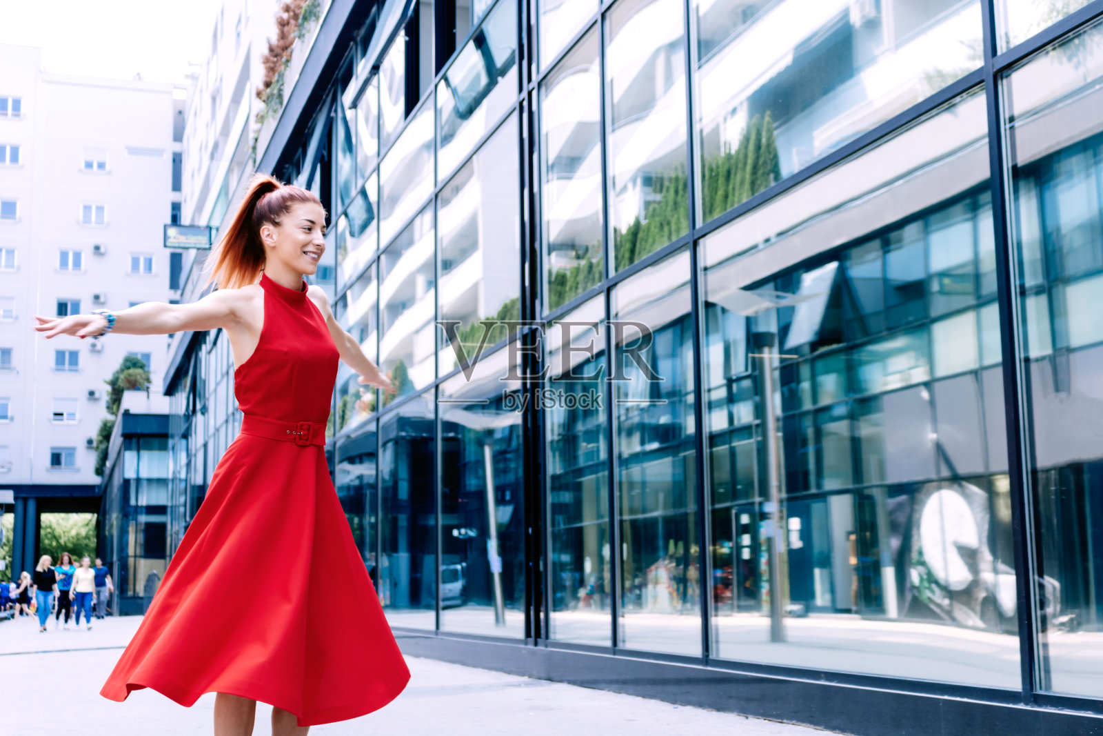 年轻无忧无虑的女人在城市里张开双臂纺纱。照片摄影图片