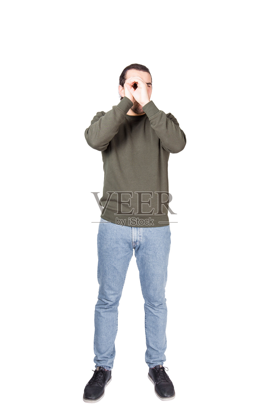 完整的肖像积极的年轻人看通过他的手作为一个望远镜手势孤立在白色的背景。照片摄影图片