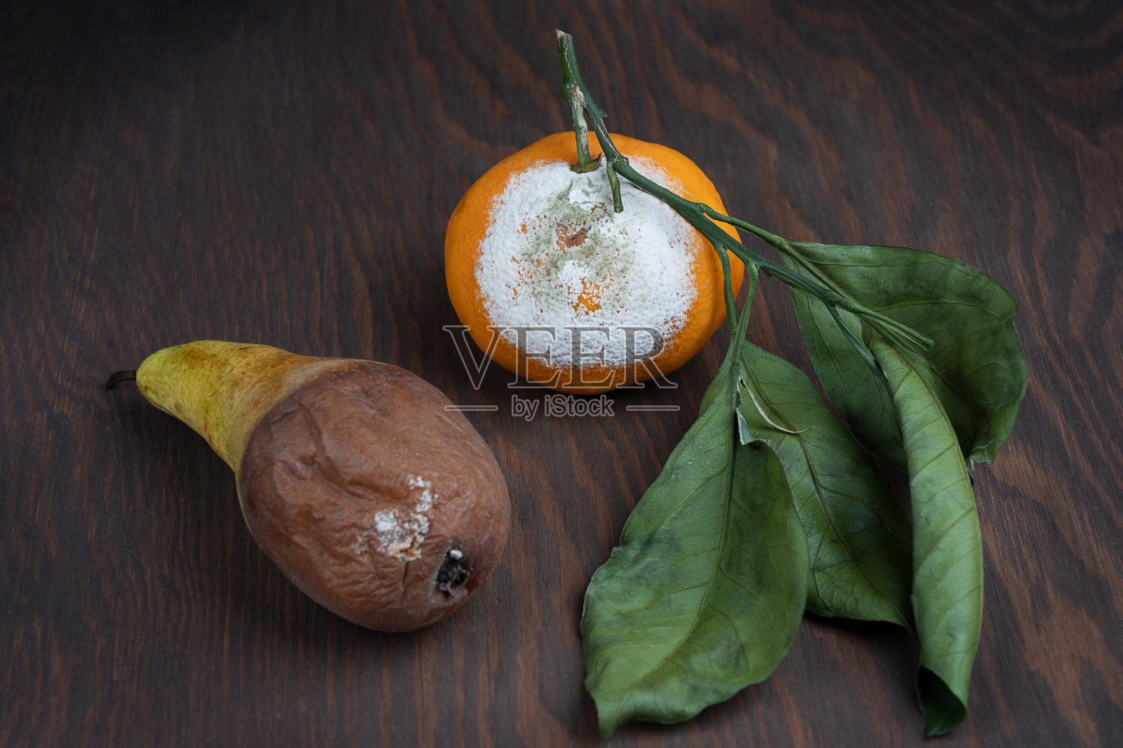 真菌发霉的柑橘和梨在深棕色的木头背景照片摄影图片