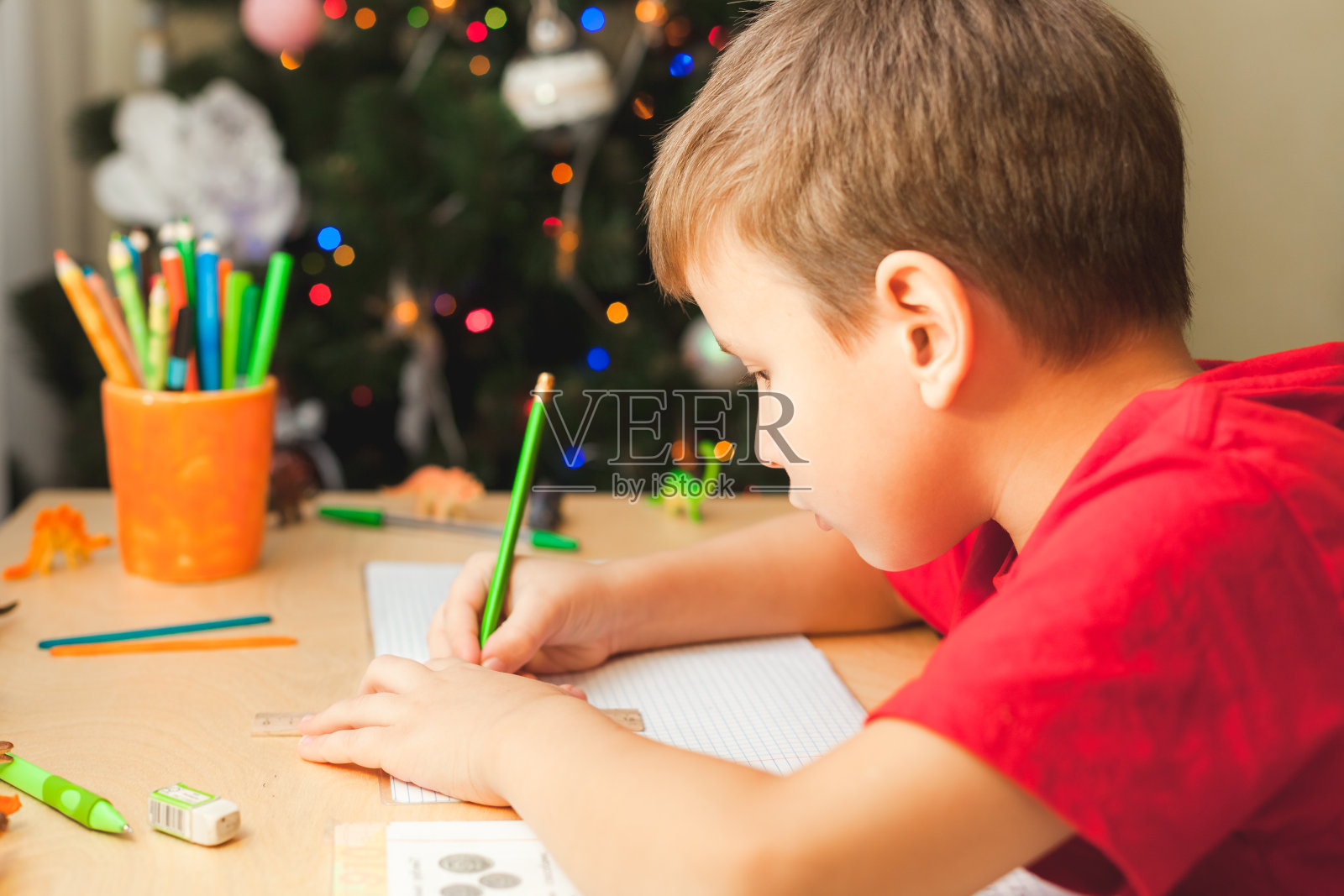7岁的男孩坐在书桌前做作业照片摄影图片
